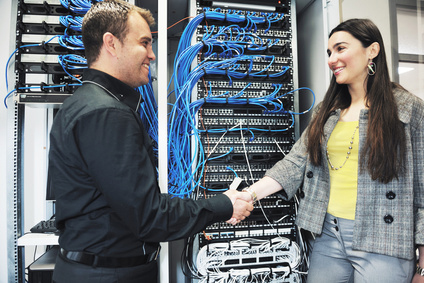 IT Guy shakes hands with a client in front of a comms cabinet